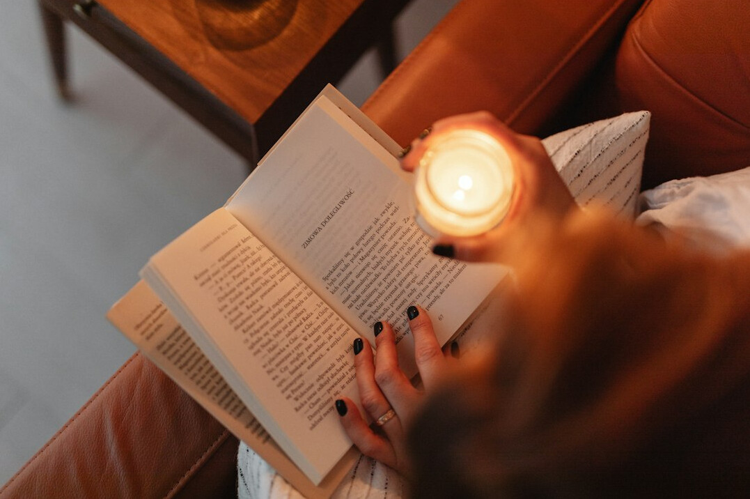 person reading book by candlelight